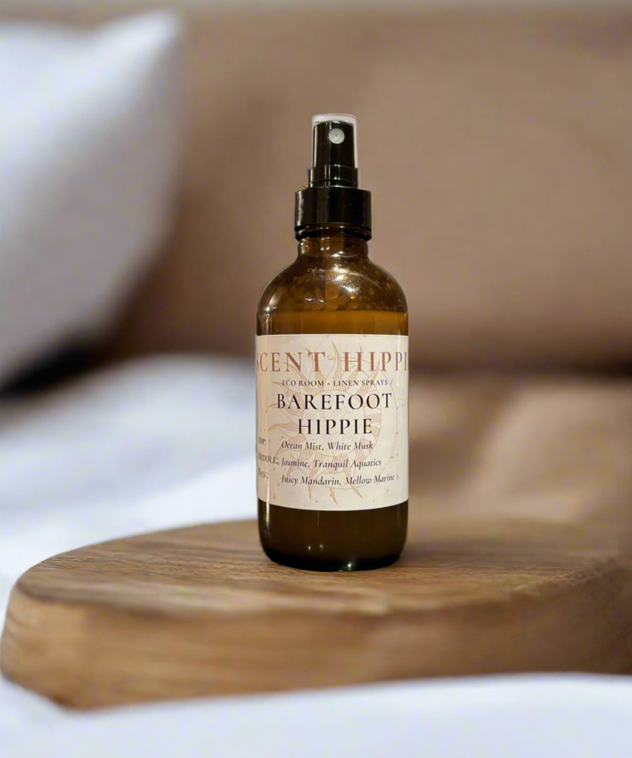 a brown spray bottle labeled "barefoot hippie" sitting on a wooden slab in a white bedroom.
