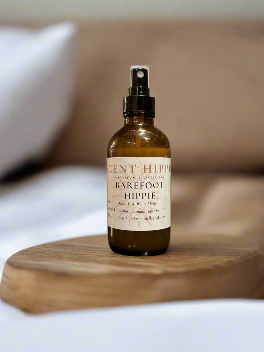 a brown spray bottle labeled "barefoot hippie" sitting on a wooden slab in a white bedroom.